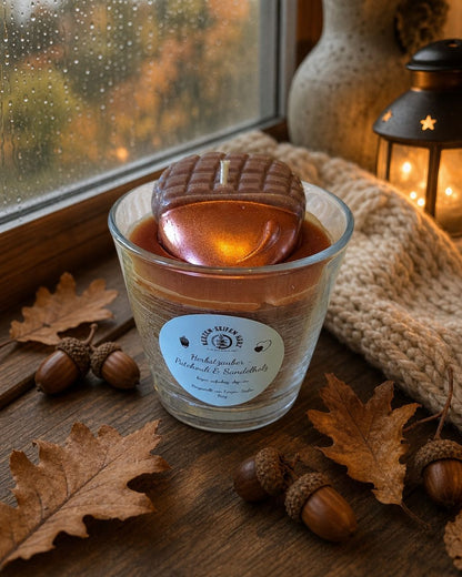 Herbstzauber-Duftkerze mit Patchouli-Sandelholz zwischen Herbstlaub und natürlicher Holzdekoration