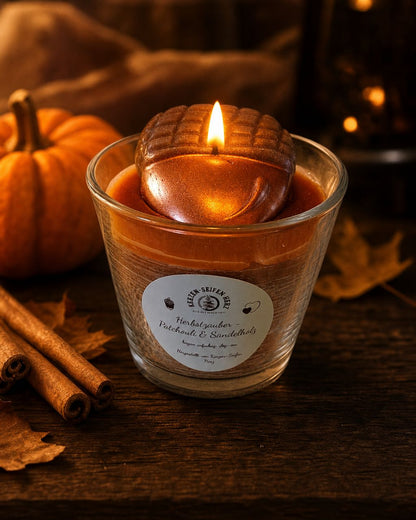 Herbstzauber-Duftkerze mit brennender Flamme in gemütlicher dunkler Herbststimmung