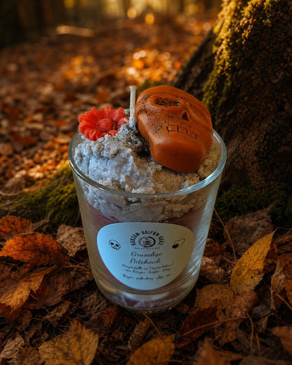 Brennende „Gruseliger Patchouli“-Duftkerze vor einer dunklen Waldkulisse