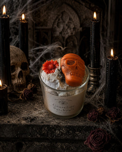 Patchouli-Kerze mit Totenkopf und Blüte in dunkler Atmosphäre mit sanften Lichtpunkten