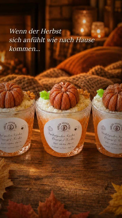 Drei Herbstzauber Kürbis Duftkerzen im Glas in gemütlicher Herbstdekoration mit warmem Licht