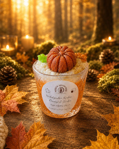 Herbstzauber Kürbis Duftkerze im Glas vor herbstlicher Waldkulisse mit warmen Farben und Herbstlaub
