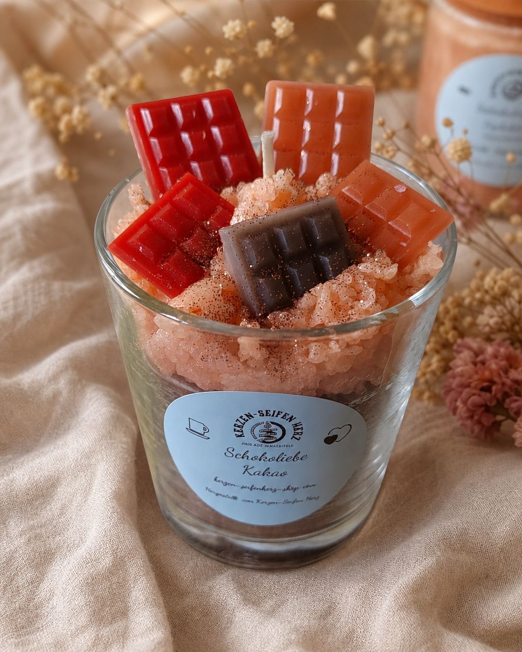 Schokoliebe-Duftkerze im Glas auf heller Decke mit liebevoll gestalteten Mini-Schokoladentafeln