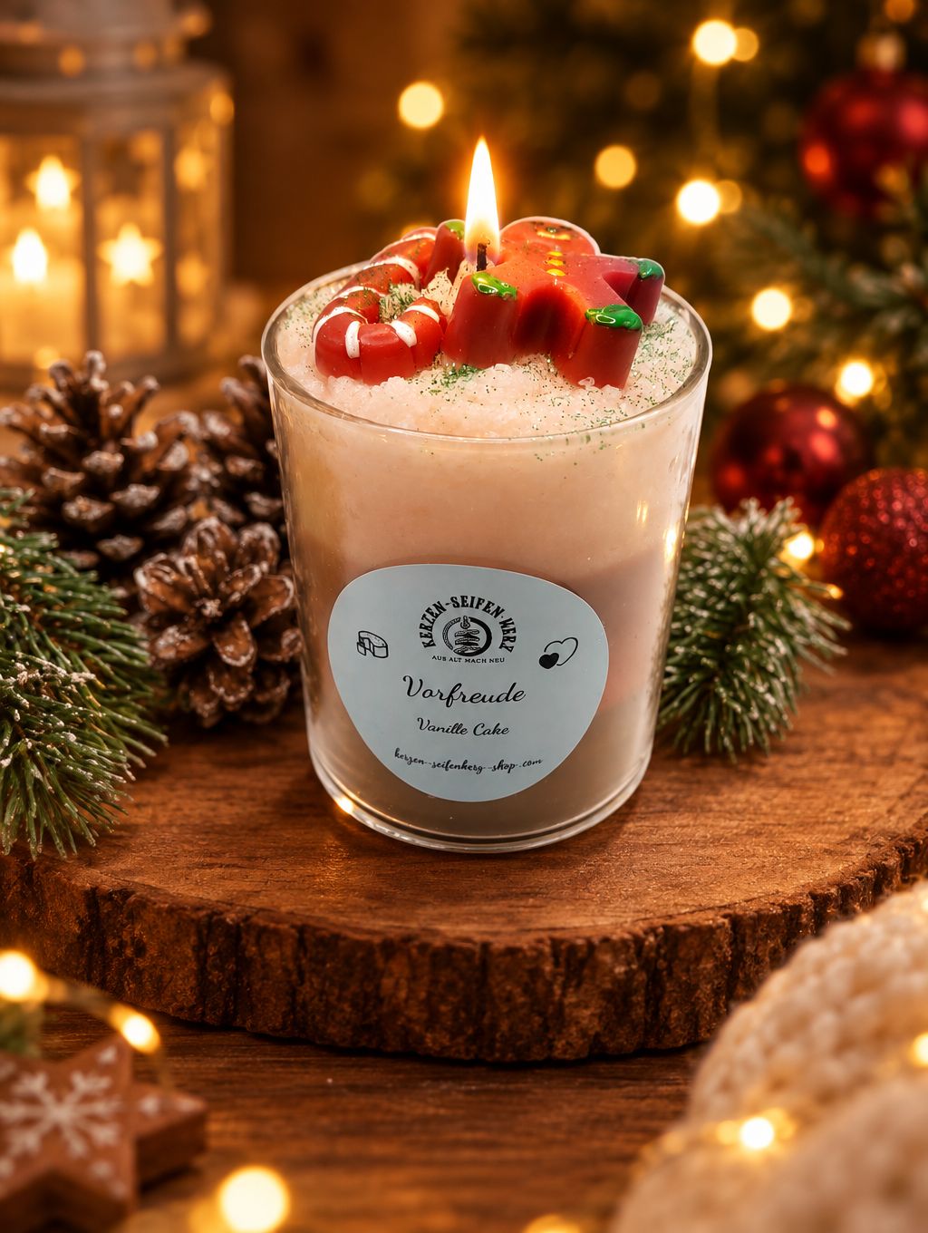 Vanillecake-Weihnachtskerze im Glas mit Lebkuchenmännchen und Zuckerstange auf Holzscheibe in festlicher Weihnachtsdekoration