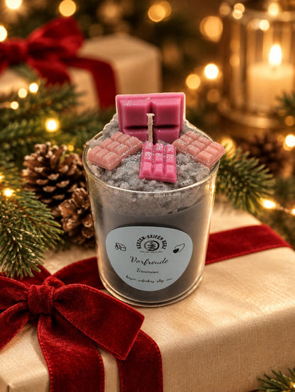 Tiramisu-Weihnachtskerze im Glas mit rosa Schokoladendekoration auf Geschenkbox mit roter Samtschleife