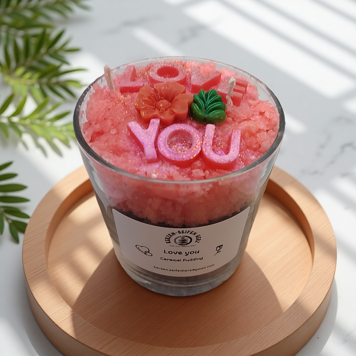 Nahaufnahme der Karamellpudding-Duftkerze mit „Love you“-Buchstaben, Blume und Blatt